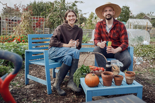 Man and woman relaxing on an allotment bench with fresh organic produce