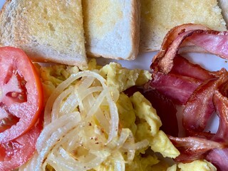Breakfast with bacon, eggs, onions, tomato and toast