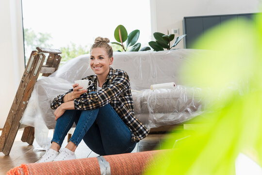 Woman relaxing with coffee during home renovation in living room