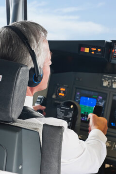 Flight captain wearing headphones navigating commercial airplane cockpit