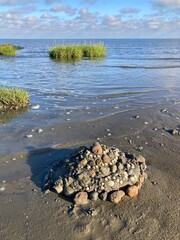 Sandburg am Strand der Nordsee mit Steinen kurz vor der &Uuml;bersp&uuml;lung durch die Flut in Cuxhaven
