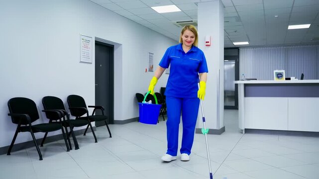 A smiling cleaner, wearing blue uniform and yellow gloves, mops a waiting room floor with chairs