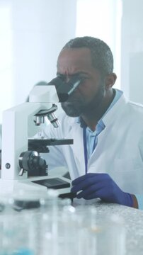 Black male scientist meticulously investigates biomedical sample using advanced microscopy techniques in lab