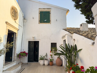 Fototapeta premium Tranquil courtyard of Vlaherna Monastery at Corfu island, Greece. Whitewashed walls, potted flowers, traditional architecture