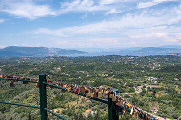Mountain and sea landscape and love locks attached to the railing, sunny summer day, scattered clouds on blue sky