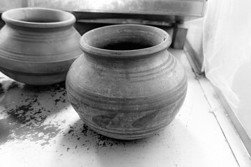 A rustic, round terracotta pot, brown earthenware, shows horizontal lines from its creation. Its a simple, traditional cooking or storage vessel.