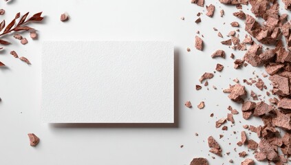 Blank white card amidst scattered cosmetic powder and plant sprig