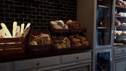 Warm light fills a charming bakery showcasing an array of freshly baked breads and pastries. Wooden shelves abound with golden crusts, inviting customers to indulge in tasty treats.