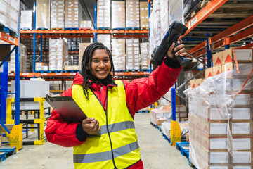 Woman warehouse worker in safety gear scanning inventory with a barcode reader in a low temperature cold storage logistics warehouse