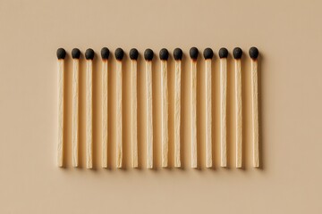 A row of unlit matches with dark red tips arranged neatly on a flat surface