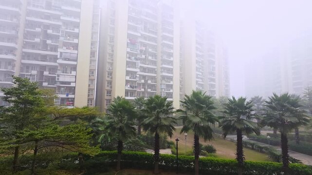 ground panning shot showing multi storey skyscraper builds hidden in the fog smog pollution in the winter in delhi gurgaon noida gaziabad showing the visibility and air quality challenges