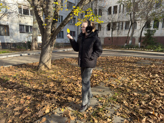 Woman autumn leaf smiles holding yellow foliage during sunny cold day