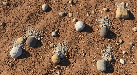 Varied sized smooth, rounded stones scattered across dry, textured reddish-brown earth with patches of lighter colored gravel.