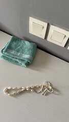 Seashell Necklace and Folded Towel on White Surface