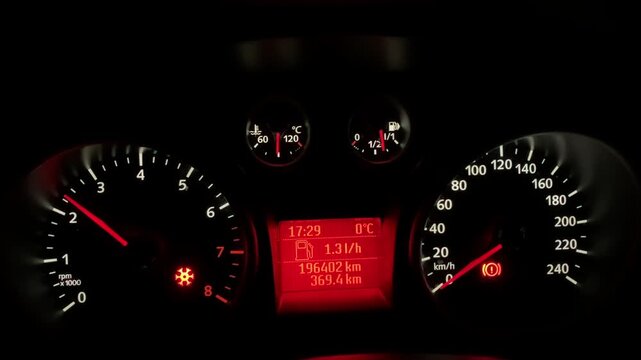A car dashboard at night, the tachometer needle moving, showing the engine speed when the accelerator pedal is pressed. Warming up a parked car in winter.