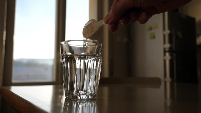 Scoop Pouring Supplement Powder into Glass of Water. Healthy Nutrition Preparation.