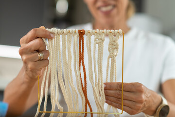 Woman reviewing tapestry progress while working in a calm home environment. Emphasizes attention to detail, color balance, and creative focus.