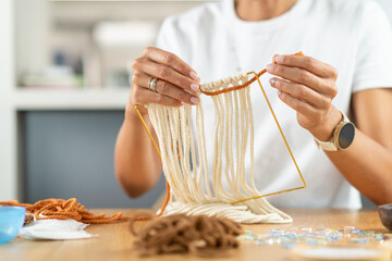 Hands of a woman weaving tapestry on a simple home loom. Highlights methodical hand movement, yarn control, and calm textile craft practice.