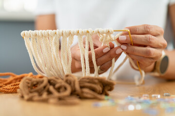Woman weaving tapestry pattern using yarn. Shows design thinking, material choice, and artistic craft flow.