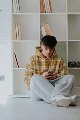young man with mobile phone at home in casual outfit