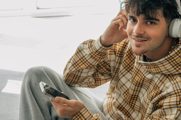 young man at home with mobile phone and headphones