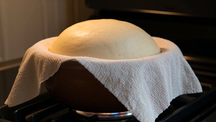 Bread dough rising in bowl with towel