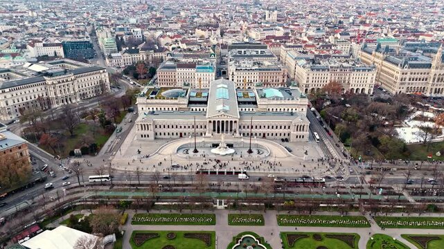 Static aerial drone shot of the Austrian Parliament Building in Vienna, framed by the surrounding cityscape with historic rooftops and broad avenues, illuminated by clear winter sunlight