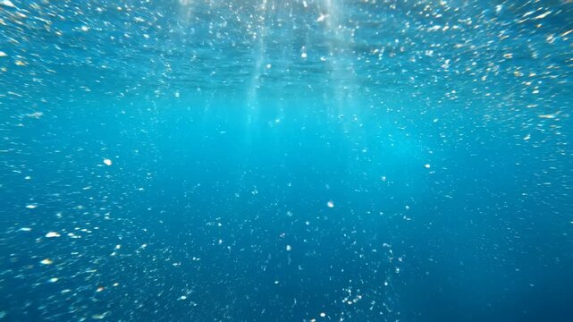 Extreme close up underwater shot capturing gentle shafts of light piercing through a submerged endless cyan blue void in slow motion calm, light rays, beautiful