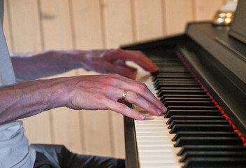 Hands playing piano keyboard in cozy home interior