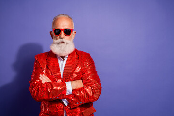 Fototapeta premium Elderly man with white beard in red sequin jacket and red sunglasses poses confidently against purple backdrop for stylish party or concert promotion