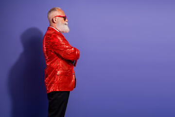 Bearded man in red sequin jacket and red glasses poses against purple background for fashion and retro party themed stock image