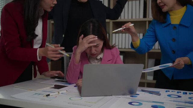 Upset young asian employee feeling stressed and overwhelmed by angry colleagues yelling and blaming her for a mistake in the office