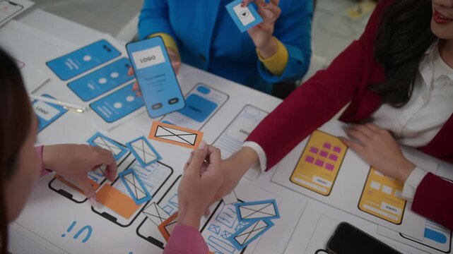 Close up view of a collaborative team of developers creating a mobile application interface, working together on a prototype for a new smartphone app