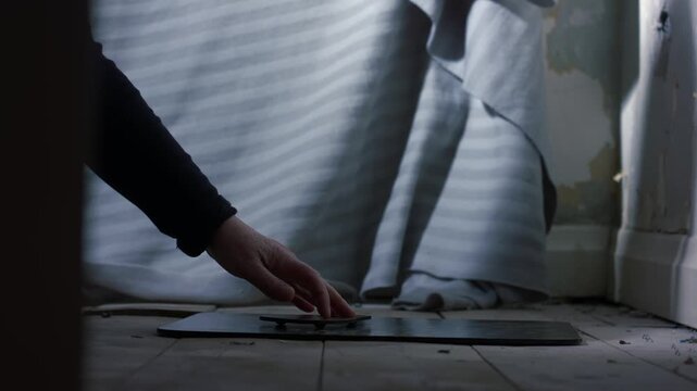 Door opens to reveal woman using spirit board in abandoned house