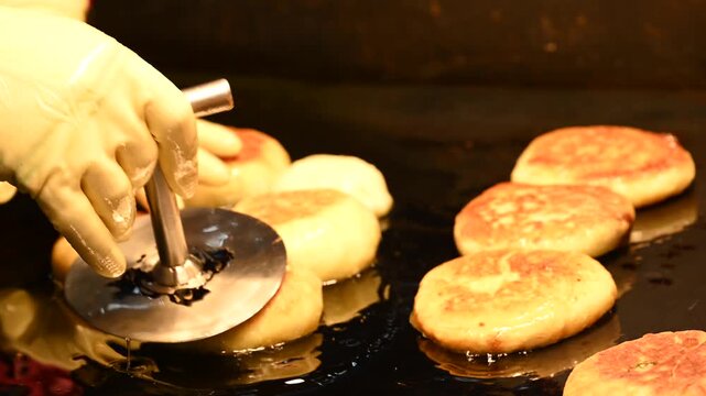 A vendor fries hotteok, a Korean sweet pancake, in hot oil at a market in Myeongdong, South Korea.