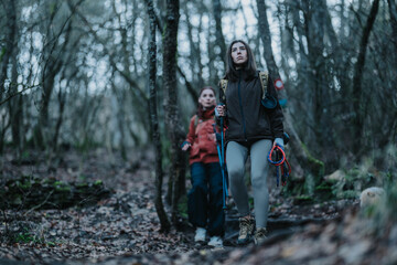 Fototapeta premium Two women hike through a forest, equipped with backpacks and trekking gear. A simple, outdoor adventure scene.