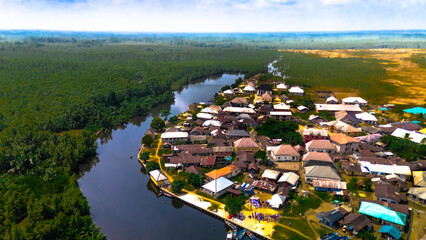 Aerial view of a vibrant community nestled beside a winding river, where rustic homes meet the lush, verdant forest, Abonnema, Port Harcourt, Nigeria.