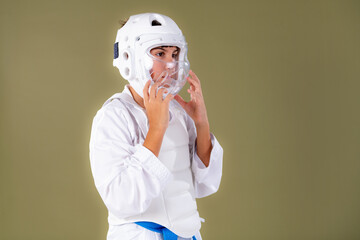 Boy in karate outfit securing protective helmet on head before practice. Emphasizes control, readiness, and structured martial arts discipline.