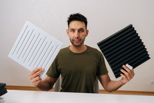 Portrait of man comparing soundproof acoustic panels for sound absorption and insulation, demonstrating options for home studio and interior sound treatment solutions, reviewing different materials.