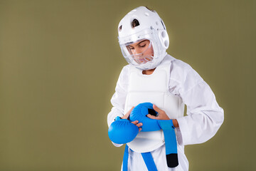 Karate student in protective sparring gear tightening gloves on hands before Shotokan practice. Shows focus, alignment, and safe martial arts preparation.