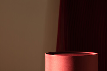 Minimalist red product podium against a dark textured background with shadows.