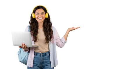 Happy Young Female Student With Laptop And Headphones Pointing At Copy Space Isolated On White
