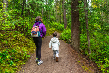 Mother and son hiking on a trail in a lush forest