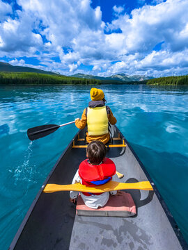 Father and son canoeing on maligne lake in jasper national park, alberta, canada