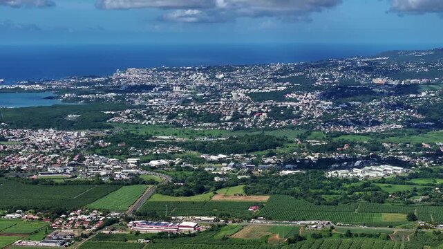 left panning across green Martinique landscape from city of Fort-de-France across Fort-de-France Bay to Martinique Aim&eacute; C&eacute;saire International Airport, Lesser Antilles, Caribbean - 4k aerial footage