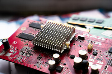 Close-up of a microchip mounted on a red printed circuit board. Electronics hardware and technology background.