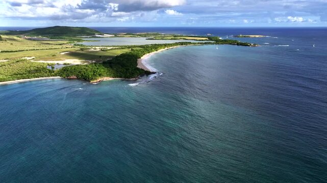 flying along famous Salines Beach in the commune of Sainte-Anne, Martinique, with people on long sandy beach and in turquoise water, as well as Etang des Salines, forest and mountain landscape around