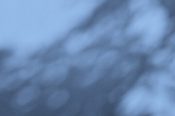 Abstract background of a light blue surface with blurred, darker shadows cast upon it.
