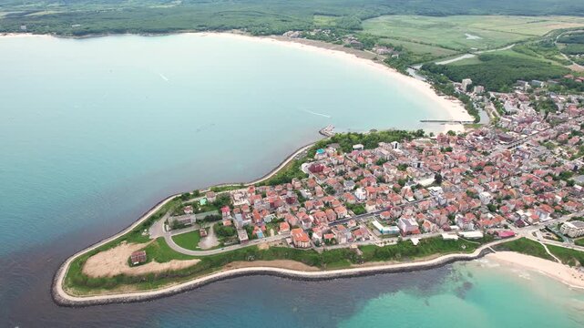 Aerial view of the vibrant Primorsko coastline, where the town meets the sea with a mix of red-roofed buildings and sandy beaches, Primorsko, Burgas, Bulgaria.