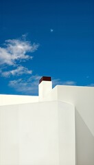 Modern white building architecture with a chimney stands prominently against a bright blue sky, showcasing minimalist design and clean geometric lines.